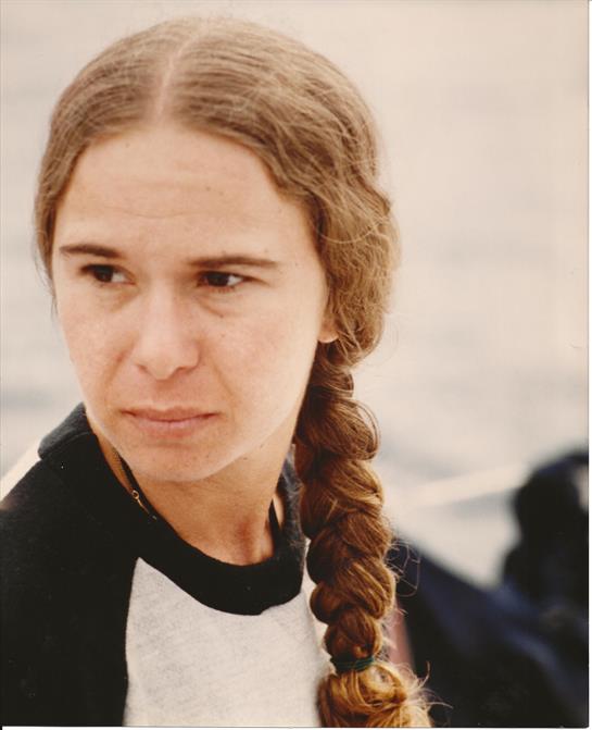 A woman with a thick braid looks pensively out at the water while enjoying a boat ride.