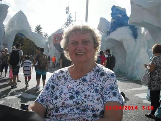 An elderly woman enjoys a theme park visit with ice attractions and happy families.