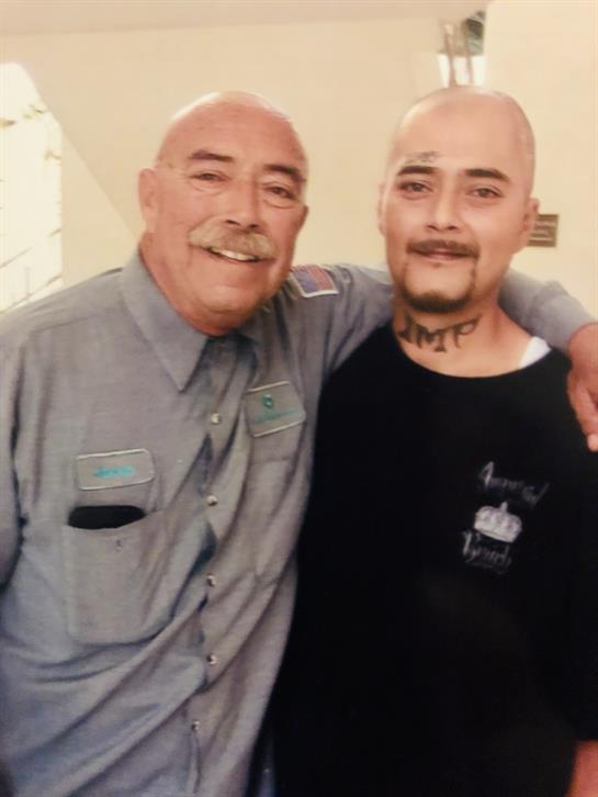 Two men share a warm moment inside a correctional facility, showcasing camaraderie and resilience.