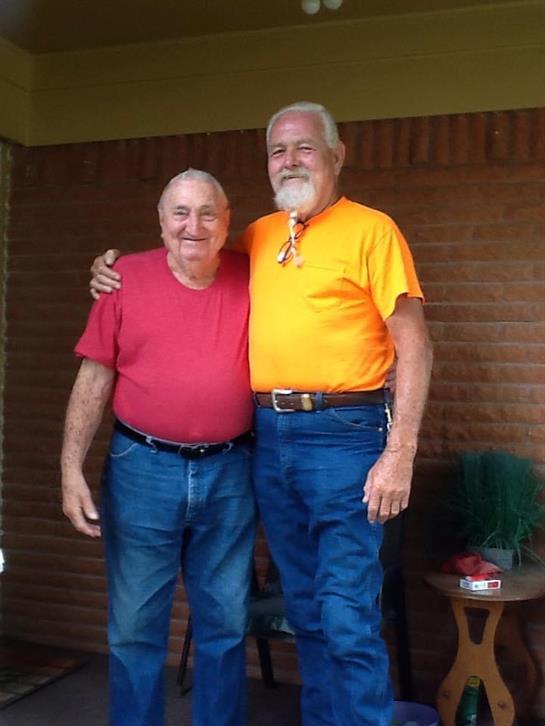 Two men stand closely together, smiling and enjoying each other's company at home.