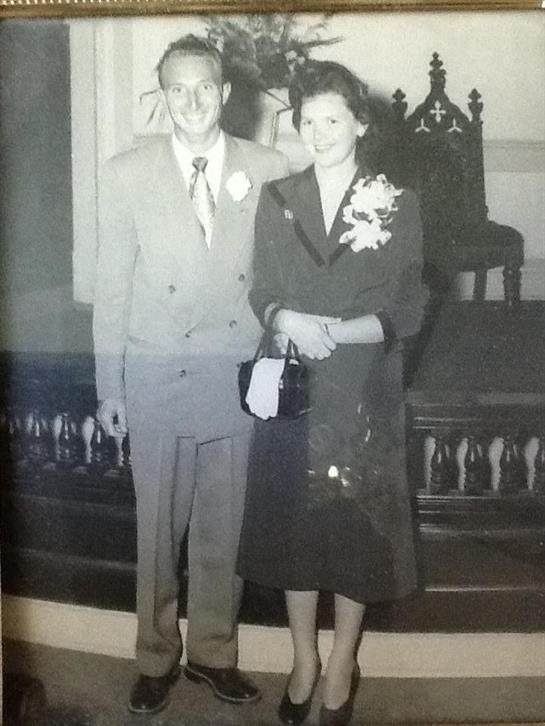 Elegant couple stands together, showcasing their formal attire in a historic setting.