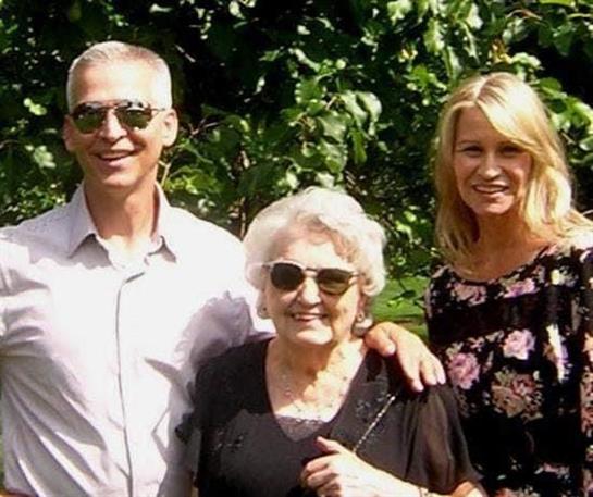 Family members are enjoying a sunny day outdoors in the garden, smiling and wearing sunglasses.
