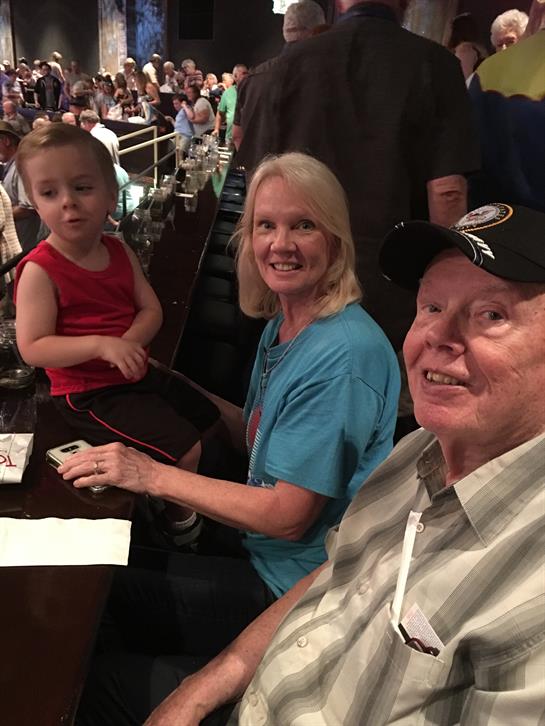 A child and two adults smile while gathered at a table during a vibrant event.