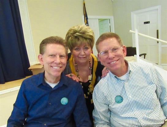 Three smiling friends pose together at a community center during a cheerful gathering.