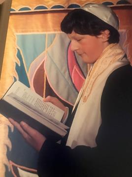 Individual engaged in reading a sacred text, surrounded by vibrant decorations and light.