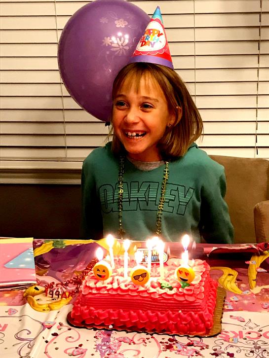 A happy girl celebrates her birthday with a colorful cake and fun decorations.