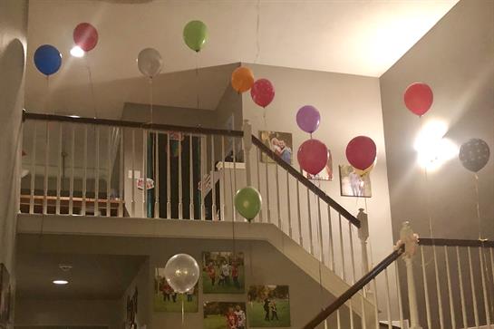 Colorful balloons hang from the ceiling, brightening the staircase during the celebration.
