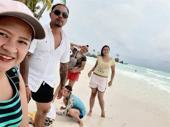Six friends gather on a sandy beach, playing and sharing laughs while clouds loom overhead.