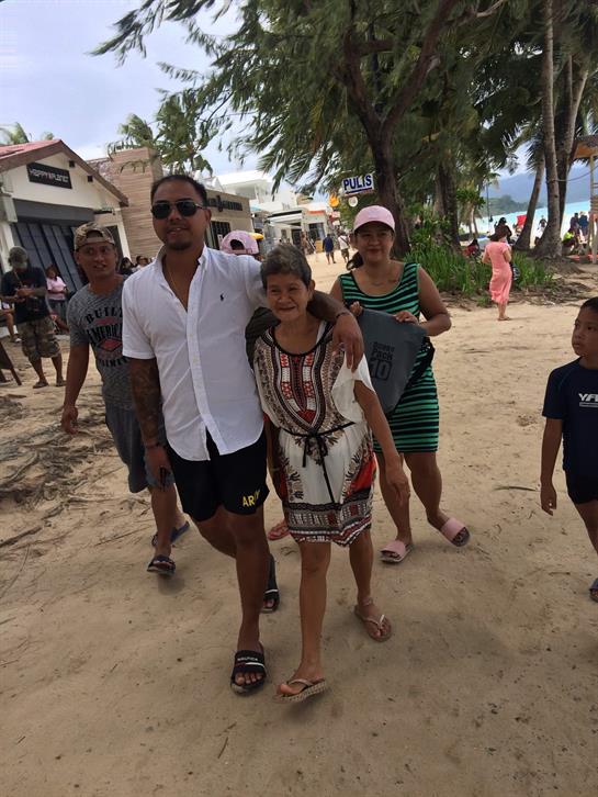 Groups of people stroll along a sandy beach while enjoying a sunny day by the ocean.