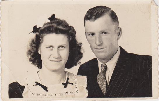 A couple poses together in formal attire, showcasing vintage hairstyles and a nostalgic atmosphere.