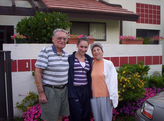 Three family members pose together in a vibrant garden filled with blooming flowers.