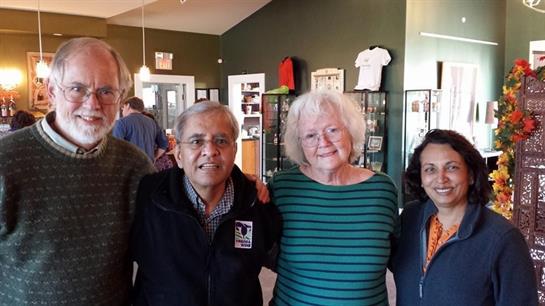 Four friends are enjoying time together at a community center, smiling warmly at each other.