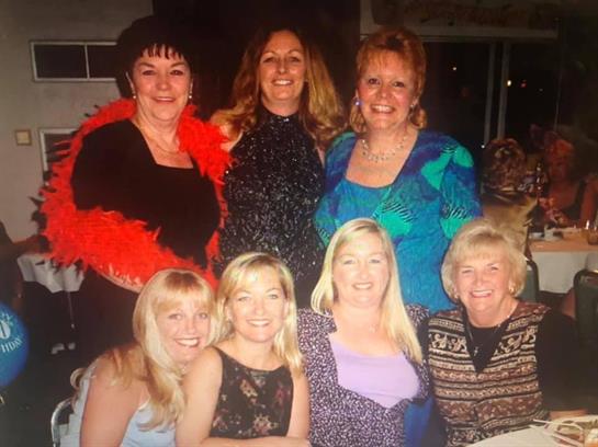 Group of women joyfully posing together, showcasing vibrant outfits and a lively atmosphere.