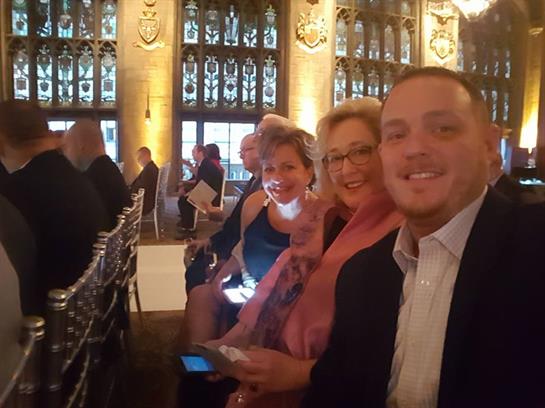 People are seated in an elegantly decorated hall, chatting and preparing for a gala event.