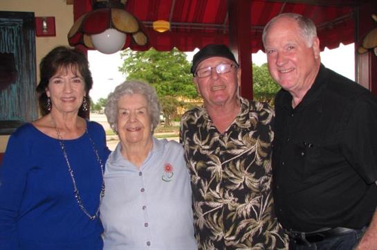 Four friends smiling and enjoying each other's company in a colorful restaurant environment.