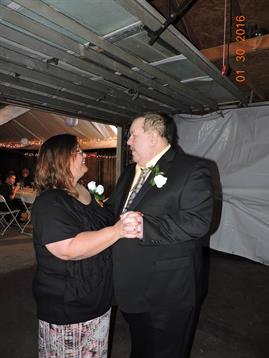 A couple shares a romantic dance together at a formal gathering in a tented setting.