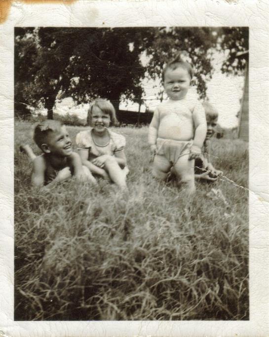 Four children enjoy a carefree moment in a grassy area, showcasing laughter and childhood joy.