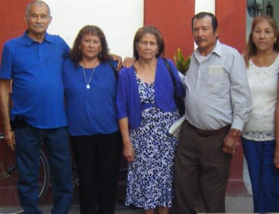 Friends stand together in a vibrant urban area, dressed in coordinated blue attire, smiling.