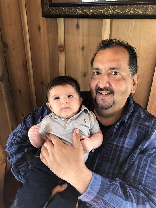 Grandfather holds his grandson lovingly in a cozy wooden cabin on a bright day.