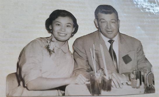 A man and a woman share cheerful moments over drinks at a restaurant in the 1950s.