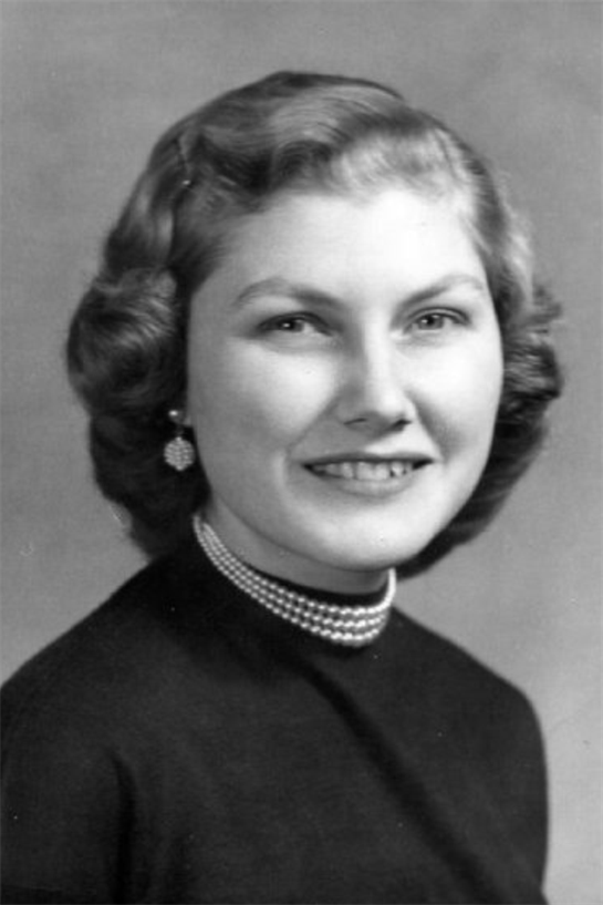 A young woman poses confidently with a vintage hairstyle and elegant pearl necklace.
