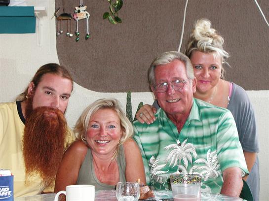 Four family members share smiles and laughter at a table in a warm, inviting space.