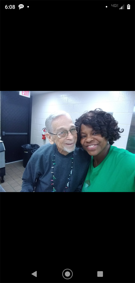 Two people share a smile in a community center, celebrating together at a joyful event.