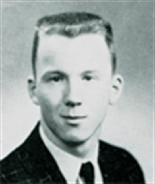 A young man in a suit and tie poses for a formal school portrait, showcasing classic hairstyle.