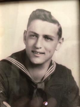 A young sailor poses confidently, wearing a classic naval uniform, with a bright smile on his face.