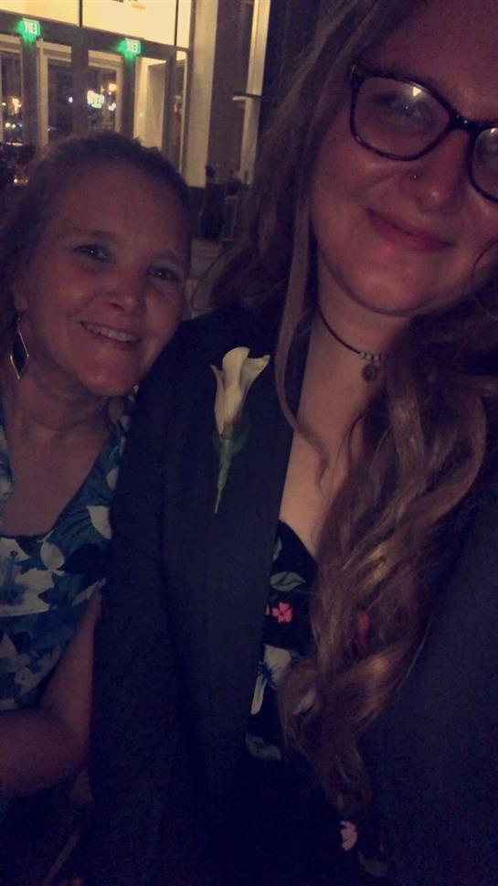 Two women smile while posing for a close-up moment at a social event during the evening.
