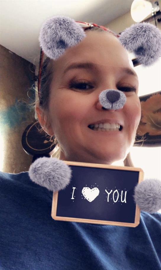 Woman displays a sign with a message of love while enjoying a playful moment indoors.