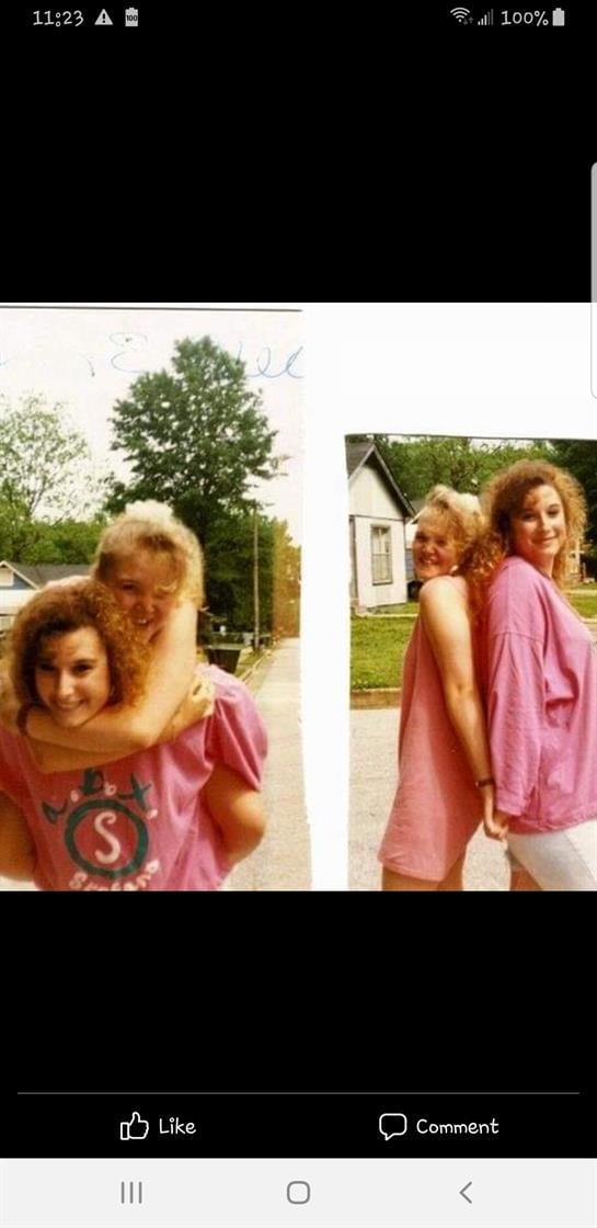 Two friends smile and embrace while having fun outdoors on a sunny day in a neighborhood.