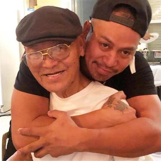 Two men express love and support through a heartfelt embrace during a family reunion.