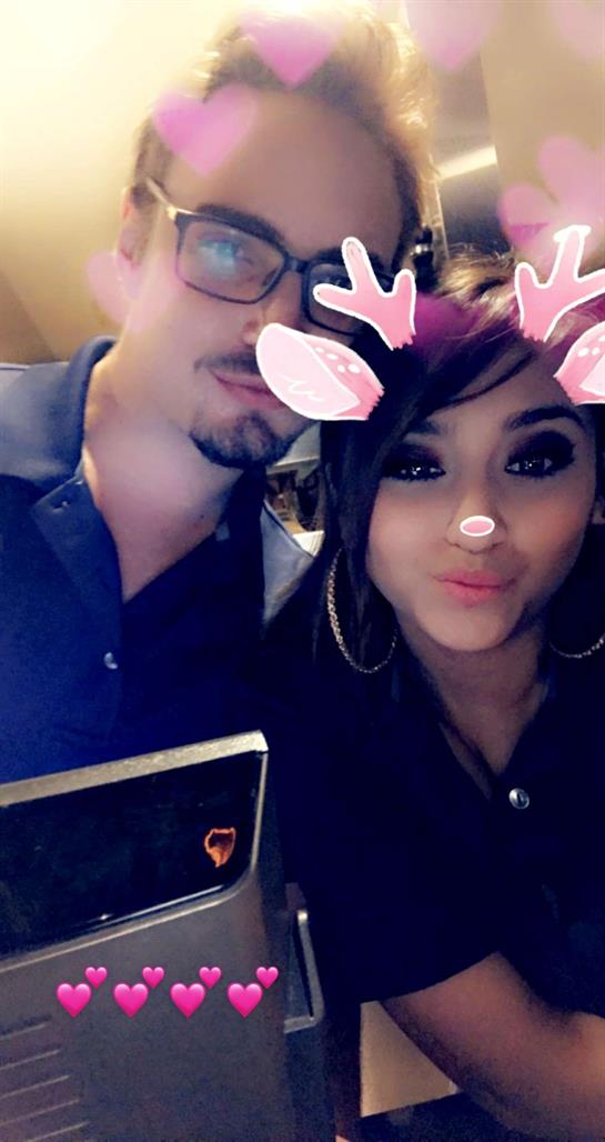 Two individuals pose closely together, smiling with playful filters during a festive gathering.