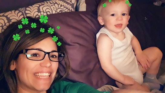 A joyful woman and a toddler share a moment on a cozy couch decorated with greenery.