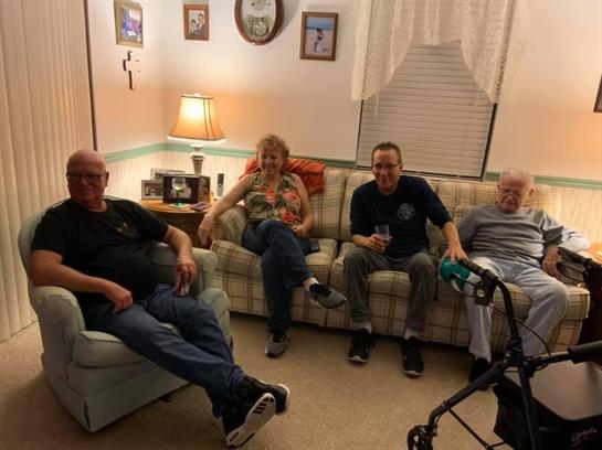 Four family members relax together in a cozy living room, engaging in laughter and conversation.