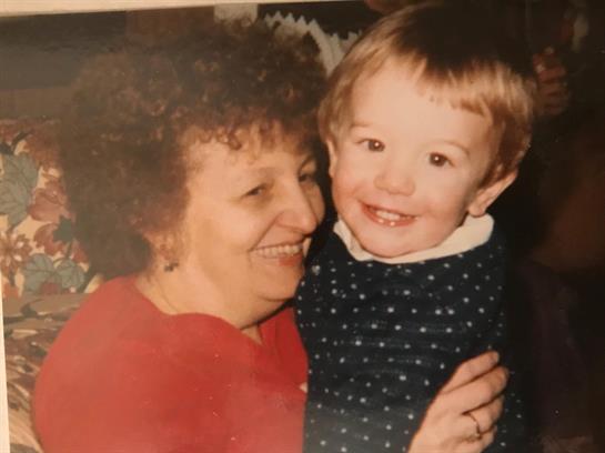 A grandmother smiles warmly while holding her happy grandson close, both enjoying a precious moment.