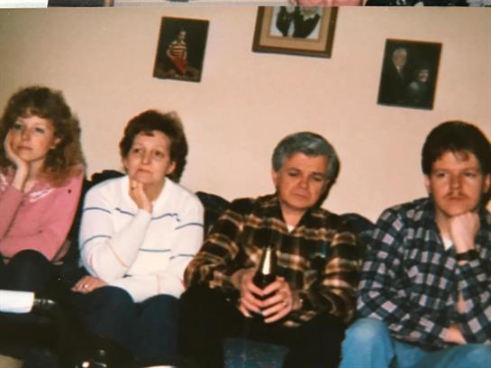 Four friends sit comfortably on a couch, chatting in a warm, inviting living room.