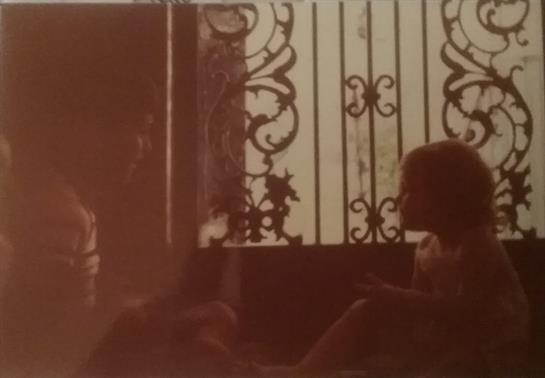 Two children sit quietly near an ornate window, enjoying a peaceful afternoon together.