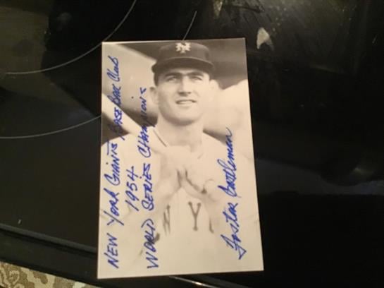 A signed black and white baseball card features a Giants player celebrating the 1954 World Series.