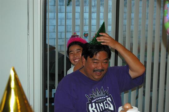 Friends and family enjoy a joyous moment wearing party hats, sharing laughter inside a house.
