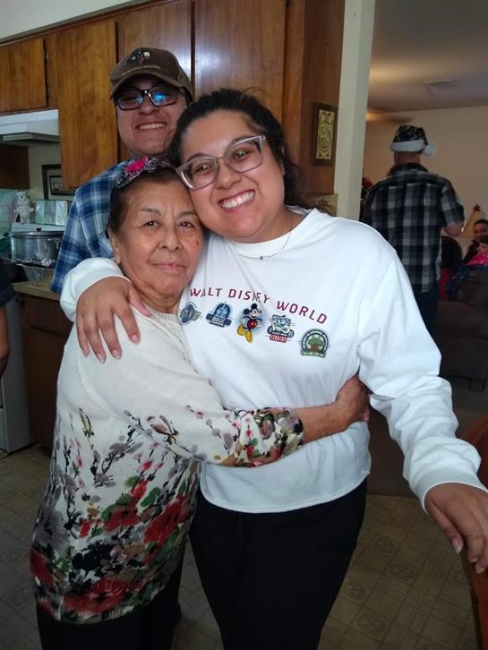 Two women embrace warmly in a cheerful family gathering surrounded by loved ones.
