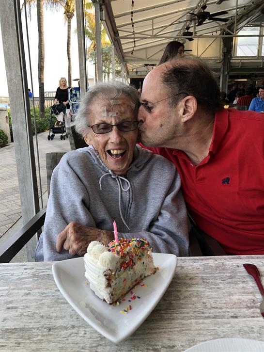 Two people share joyful moments at a cafe, celebrating together with a cake and laughter.