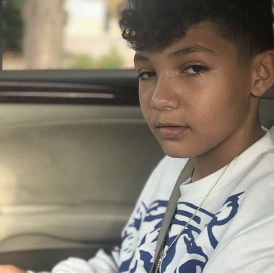 A young boy sits in a car, confidently gazing out the window in the daylight.