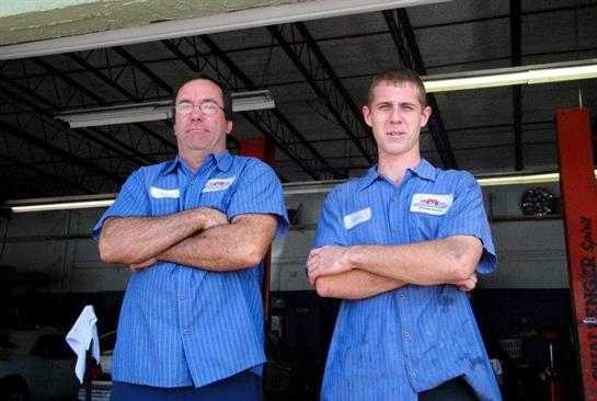Mechanics stand side by side, arms crossed, showing professionalism and camaraderie.