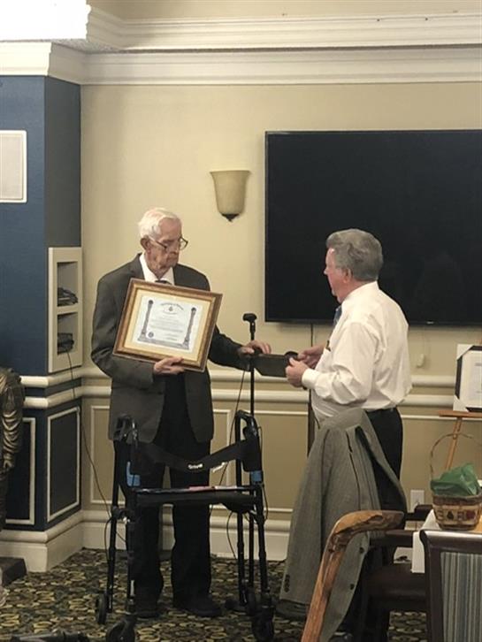 Two men are exchanging an award in a formal setting, highlighting a moment of recognition and honor.