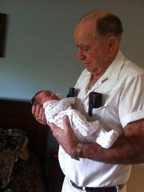 A grandfather lovingly cradles his newborn grandchild in a warm and inviting living room.