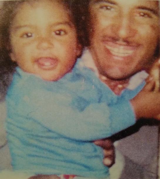 A joyful child is being held by a smiling man in a cozy setting, radiating happiness.