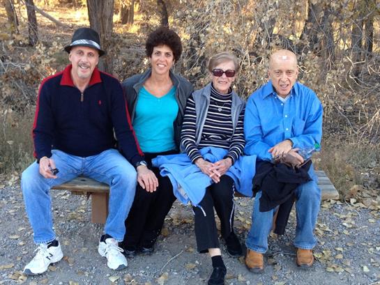 Seniors relax on a bench, smiling in a peaceful outdoor setting.