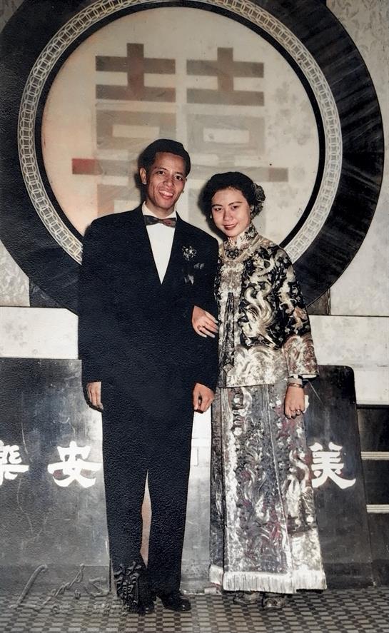 A stylish couple smiles together in formal attire at a special event in an elegant venue.